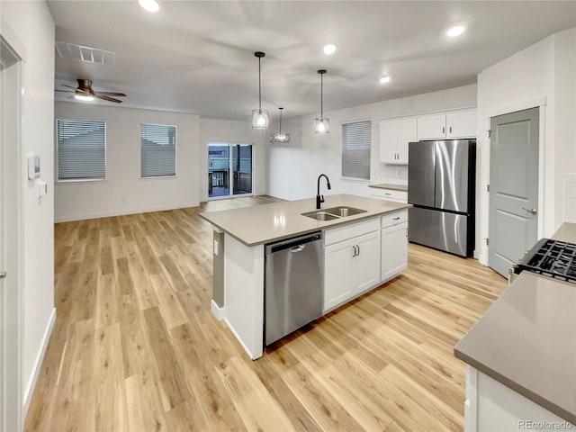 kitchen featuring visible vents, light wood-style flooring, appliances with stainless steel finishes, white cabinetry, and a sink