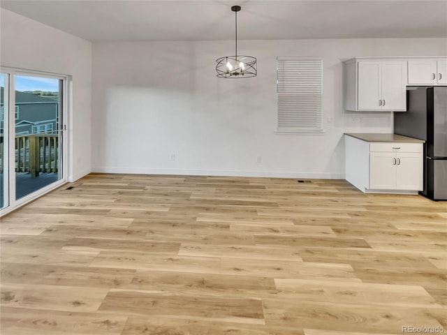 unfurnished dining area with baseboards, a chandelier, and light wood-style floors