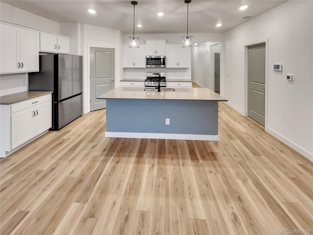 kitchen featuring white cabinets, light wood-style flooring, stainless steel appliances, and a sink