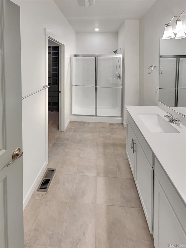 bathroom with a stall shower, vanity, and visible vents