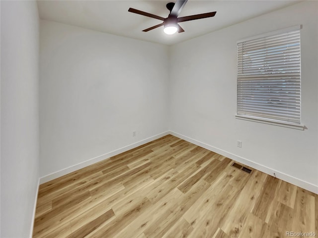 spare room featuring light wood finished floors, baseboards, visible vents, and a ceiling fan