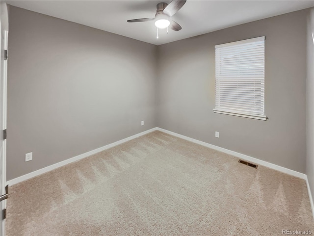 carpeted spare room with a ceiling fan, visible vents, and baseboards