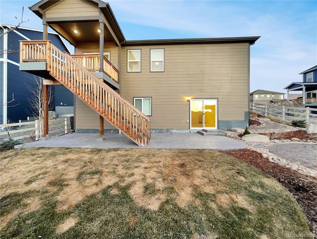 rear view of house with a patio, a yard, stairway, and fence