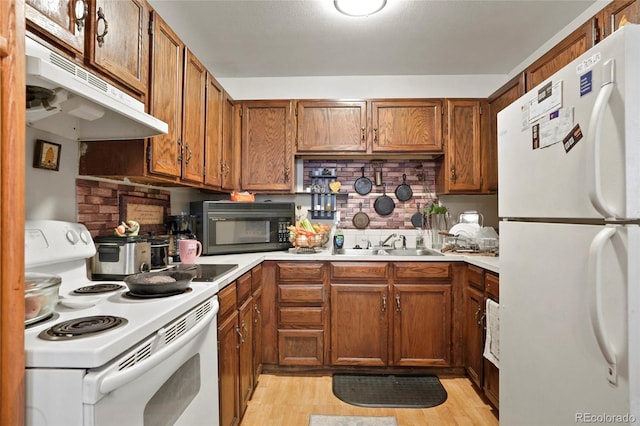 kitchen featuring backsplash, sink, light hardwood / wood-style floors, and white appliances