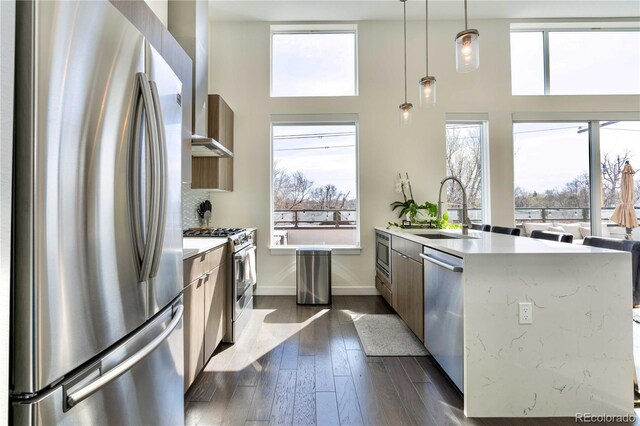 kitchen with appliances with stainless steel finishes, sink, hanging light fixtures, and plenty of natural light