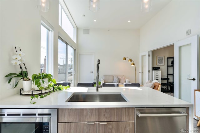 kitchen with light stone countertops, appliances with stainless steel finishes, sink, and a towering ceiling