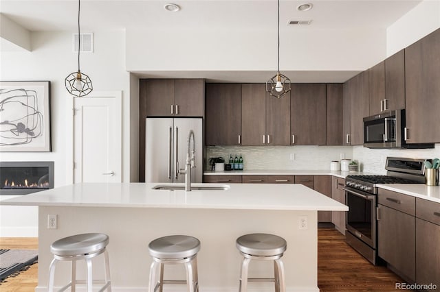3308 W 17th Ave, Denver, CO 80204 - kitchen with high end appliances, a kitchen bar, tasteful backsplash, and dark wood finished floors