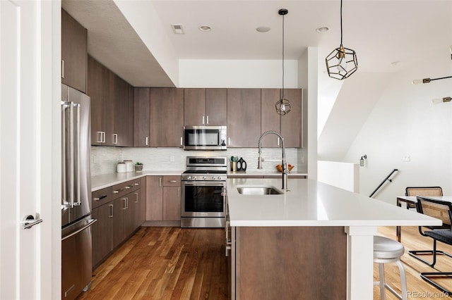 3308 W 17th Ave, Denver, CO 80204 - kitchen with appliances with stainless steel finishes, dark wood finished floors, a breakfast bar, light countertops, and decorative backsplash