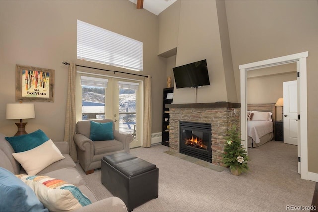 living area featuring carpet, french doors, a stone fireplace, and a high ceiling