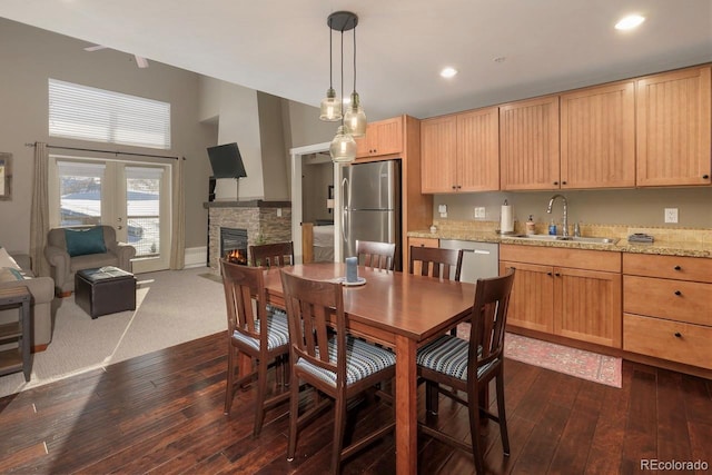 dining area with recessed lighting, dark wood-type flooring, and a stone fireplace