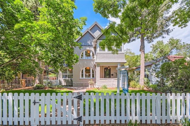 victorian home featuring a fenced front yard and stucco siding