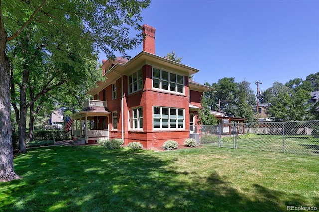 back of house with a balcony, central air condition unit, and a yard