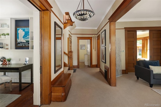 hallway featuring carpet flooring, ornamental molding, and an inviting chandelier