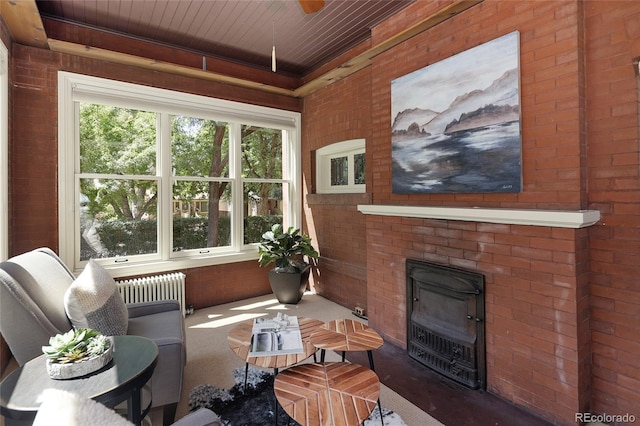 interior space with wood ceiling, radiator heating unit, and a brick fireplace