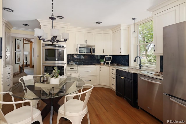 kitchen with backsplash, sink, appliances with stainless steel finishes, dark hardwood / wood-style floors, and pendant lighting