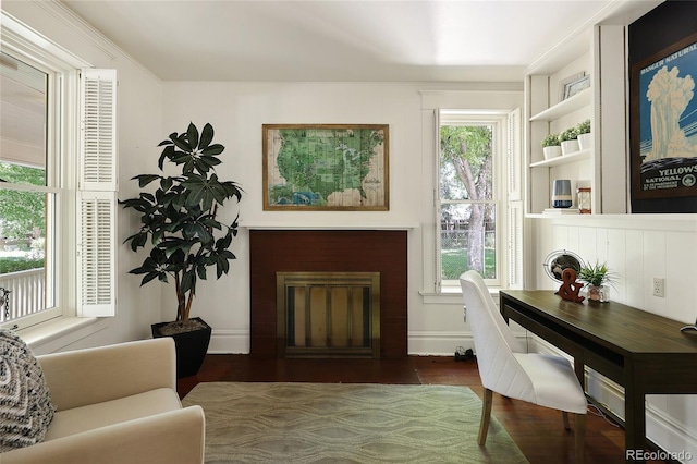 office area featuring a brick fireplace, plenty of natural light, dark hardwood / wood-style flooring, and built in shelves