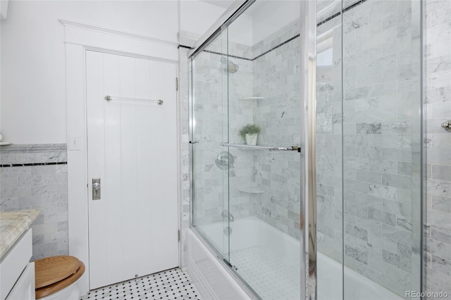 full bathroom with tile walls, tile patterned flooring, vanity, combined bath / shower with glass door, and toilet