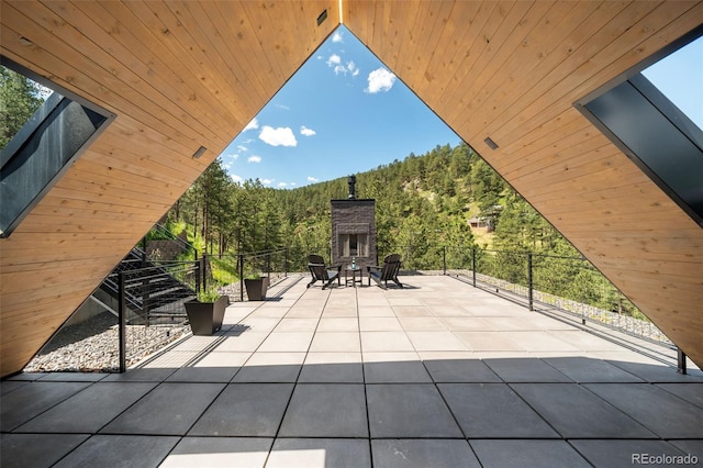 365 Bow Mountain Rd, Boulder, CO 80302 - view of patio / terrace featuring an outdoor stone fireplace and a view of trees