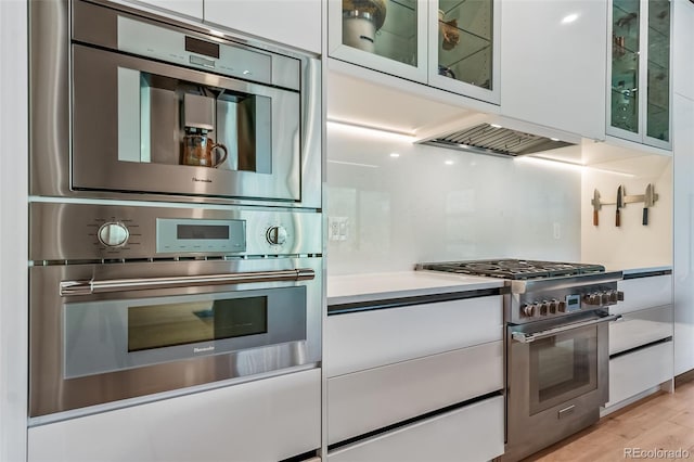 365 Bow Mountain Rd, Boulder, CO 80302 - kitchen featuring appliances with stainless steel finishes, white cabinetry, light countertops, light wood-type flooring, and glass insert cabinets