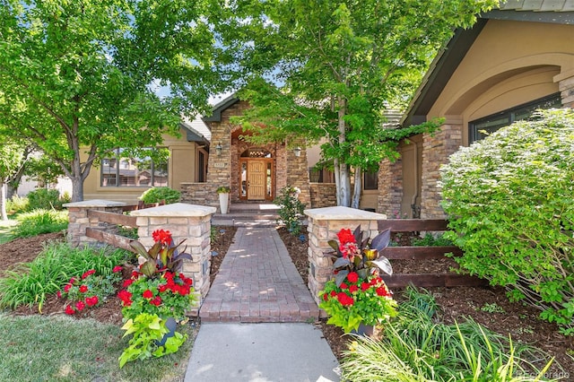 view of exterior entry with stone siding and covered porch