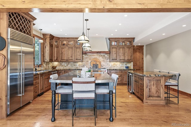 kitchen with wine cooler, a center island with sink, custom range hood, and built in fridge