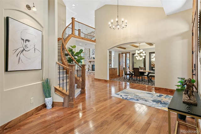 foyer entrance featuring baseboards, arched walkways, stairs, wood-type flooring, and a notable chandelier