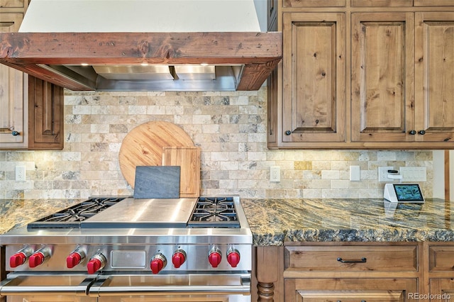 kitchen featuring premium range hood, brown cabinets, backsplash, and high end stove