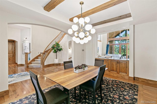 dining space featuring stairway, beam ceiling, arched walkways, light wood-style floors, and a chandelier