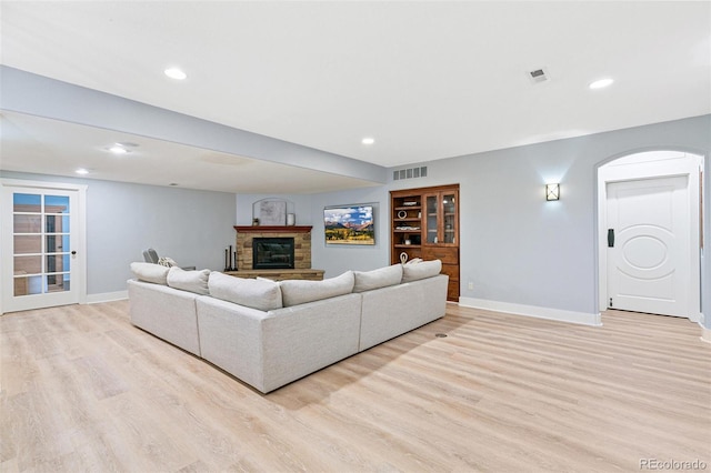 living area with visible vents, a fireplace, light wood-type flooring, and baseboards