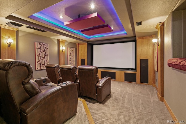 cinema room featuring a tray ceiling, light colored carpet, visible vents, and baseboards