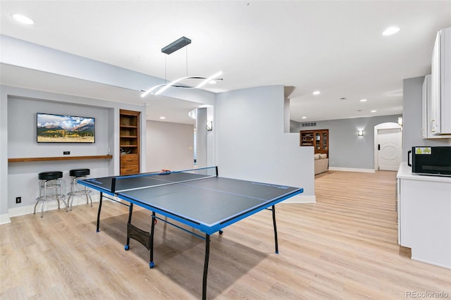 game room featuring arched walkways, recessed lighting, baseboards, and light wood-style floors