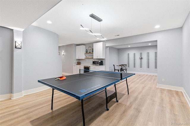 rec room with baseboards and light wood finished floors