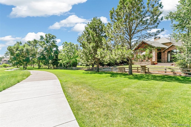 view of home's community with a lawn and fence