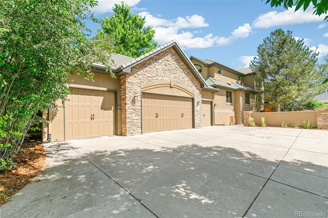 view of front of property with fence, an attached garage, stucco siding, concrete driveway, and a tile roof