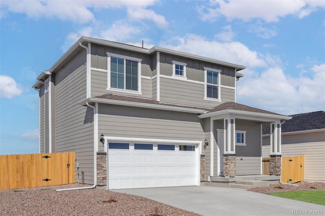view of front of home with stone siding, driveway, fence, and a garage