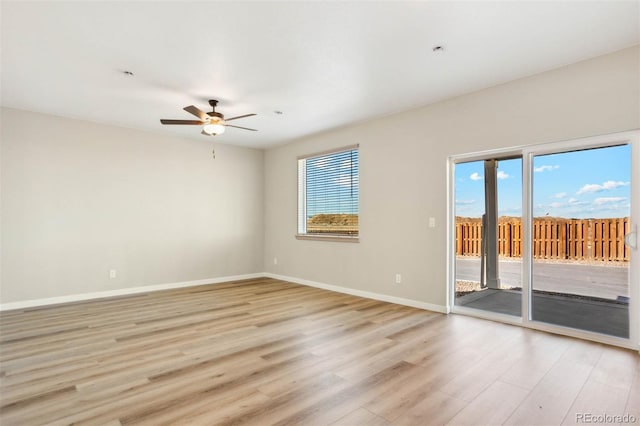 empty room featuring a ceiling fan, baseboards, light wood-type flooring, and a healthy amount of sunlight