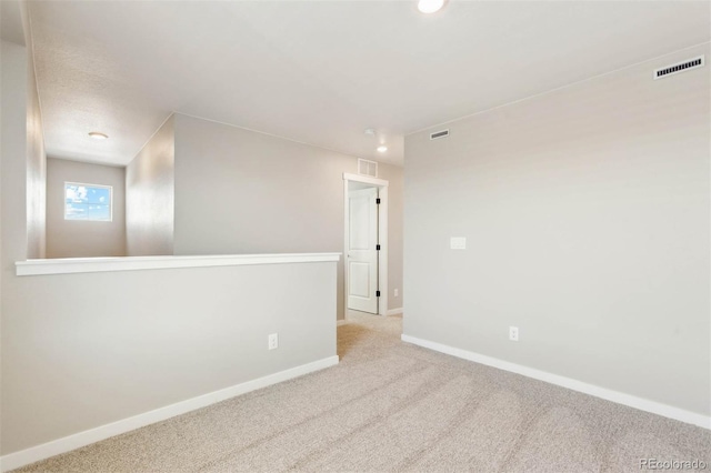 empty room with baseboards, visible vents, and carpet floors