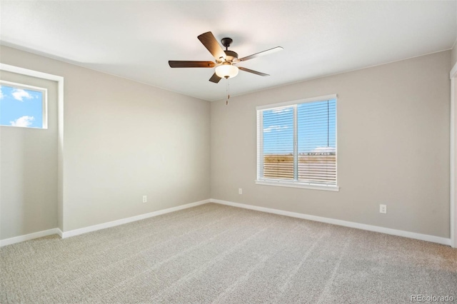 empty room with light colored carpet, baseboards, and a ceiling fan