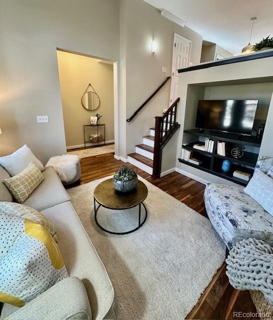 living room with baseboards, wood finished floors, and stairs