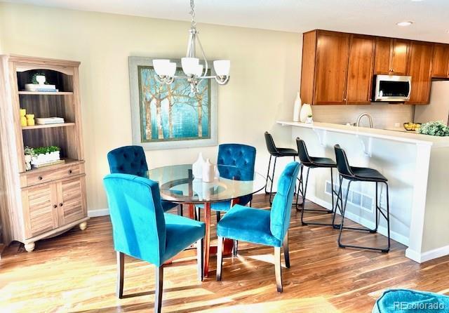 dining space with recessed lighting, baseboards, a notable chandelier, and light wood-type flooring