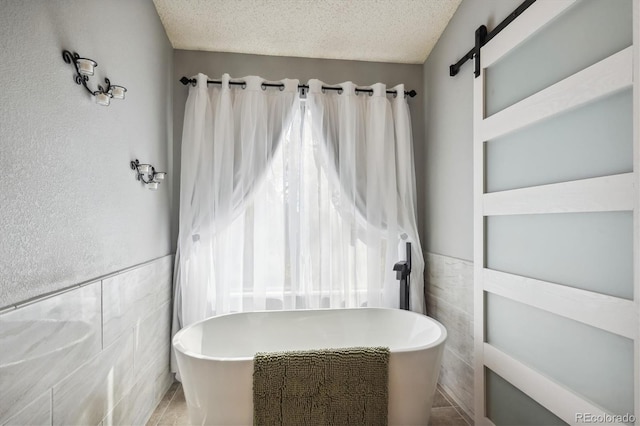 bathroom featuring tile walls, a textured ceiling, tile patterned flooring, and a bathing tub