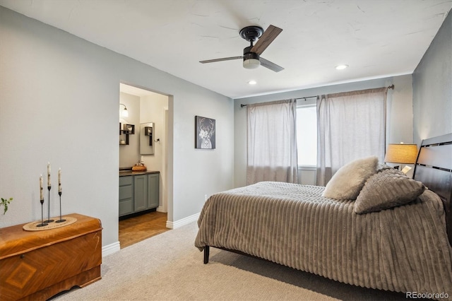 bedroom featuring connected bathroom, light carpet, and ceiling fan