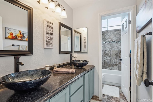 full bathroom with vanity, tiled shower / bath combo, and toilet