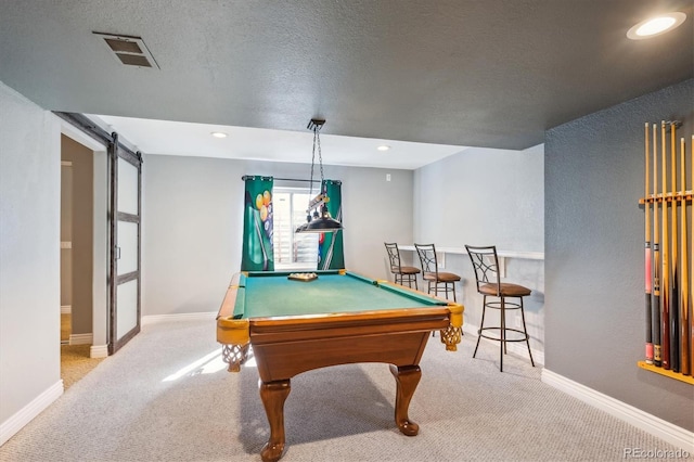 recreation room with pool table, a barn door, light carpet, and a textured ceiling