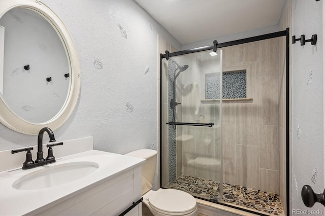 bathroom with a shower with door, vanity, and toilet