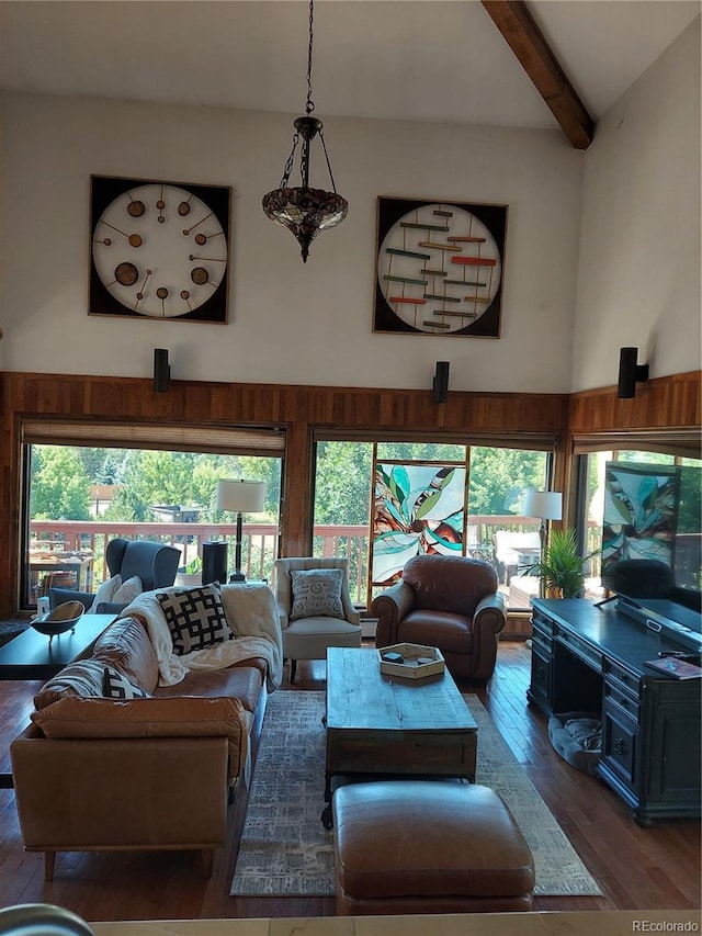 living room with beam ceiling, a towering ceiling, dark hardwood / wood-style floors, and a healthy amount of sunlight