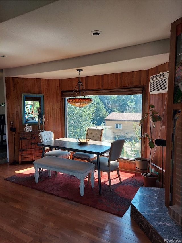 dining space featuring a wall mounted air conditioner, dark hardwood / wood-style floors, and wood walls