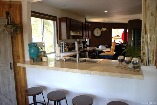 kitchen featuring sink, black refrigerator, a breakfast bar area, and kitchen peninsula