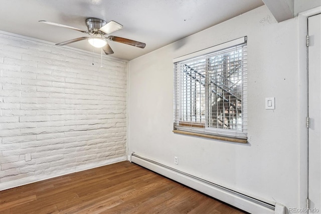 empty room featuring ceiling fan, brick wall, hardwood / wood-style floors, and baseboard heating