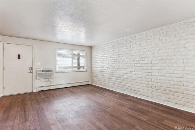 interior space with dark wood-type flooring, a wall mounted air conditioner, a textured ceiling, a baseboard radiator, and brick wall